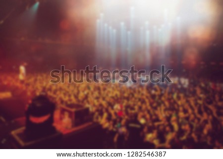 Blurred background of music festival in nightclub.View from stage on concert audience raving on dance floor in the club