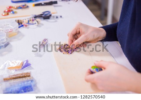 Professional jewelry designer making handmade brooch with beads in studio, workshop. Fashion, creativity and handmade concept Royalty-Free Stock Photo #1282570540