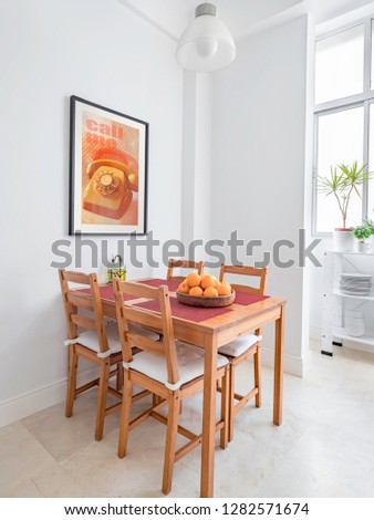 Cozy wooden table and chairs, picture frame in a spacious modern kitchen.