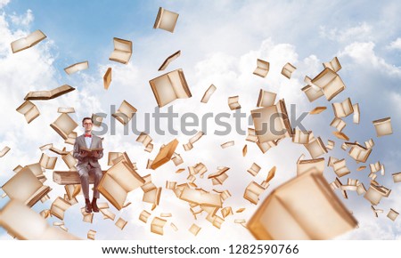 Funny man in red glasses and suit sitting on book and reading