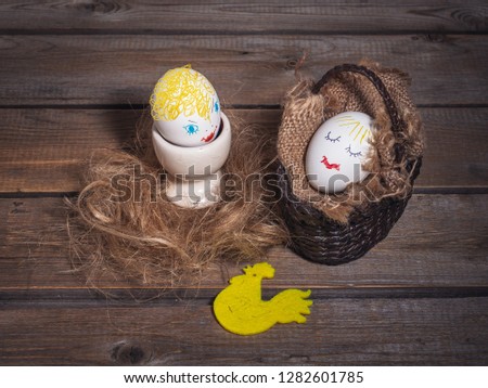 Two funny eggs with painted faces on wooden background. Easter card.