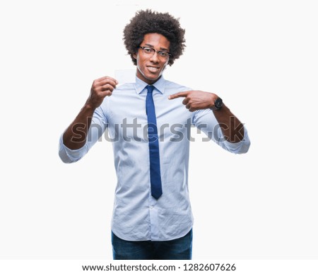 Afro american man holding visit card over isolated background with surprise face pointing finger to himself