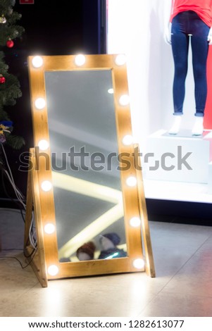 view mirror with light bulbs around the perimeter on the background of shop windows with mannequin