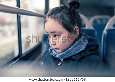 The cute little Asian girl smiled on the bus.