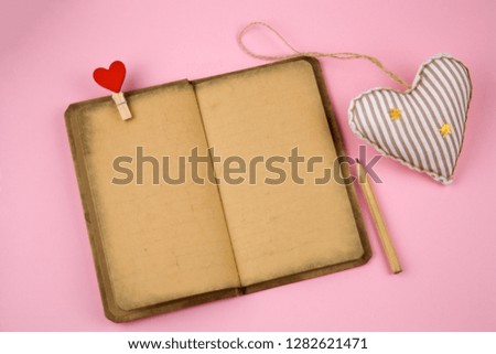 top view open book with antique paperwith place for text and soft toy in a shape of heart pastel pink background