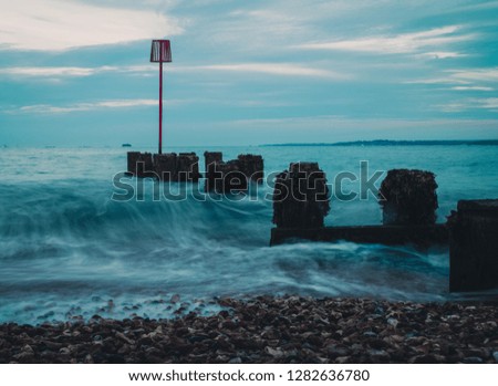 Beautiful British South Coast Shoreline in the early evening.

Coast protection at the south coast of England. Waves hitting groynes in the evening.