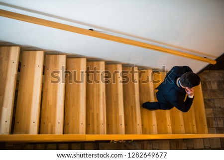 elegant man descends on internal wooden stairs Royalty-Free Stock Photo #1282649677