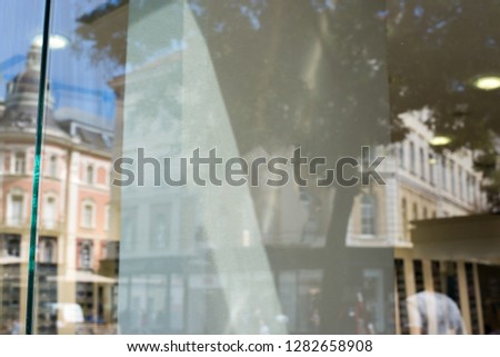 Empty shop window for logo, brand mockup. City street and buildings in window reflection.
