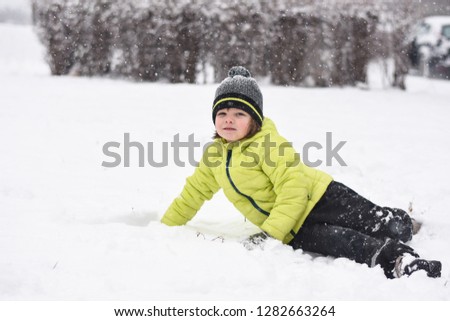 Boy falls down on snow. Winter fun. Child is rolling in the snow