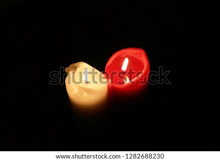 Two burning candles, white and red.