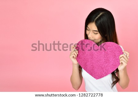 Portrait beautiful Asian girl holding pink heart sign on pink background, happy valentine day concept. Caucasian model 