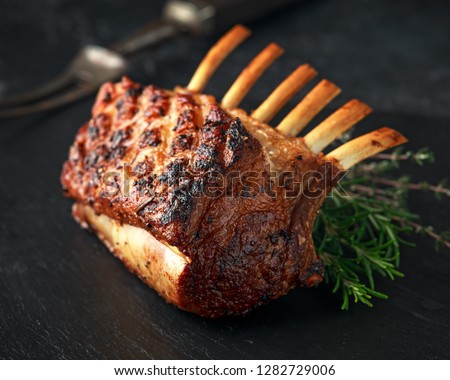 Lamb rack roasted with herbs on stone board Royalty-Free Stock Photo #1282729006