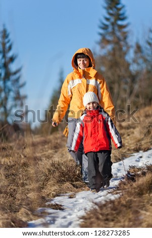 Daughter and mother hiking a snow covered path in the forest late winter
