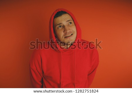 Crazy and charismatic guy posing on an orange background. A man in a red tracksuit.
