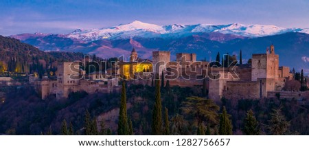 Alhambra historical monument at sunset with Sierra Nevada and its snowy mountains in the background and the Veleta peak. Photo taken from San Nicolas viewpoint in Granada, Andalusia, Spain