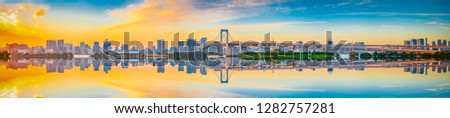 Sunset panorama view of Tokyo skyline and Rainbow Bridge with reflection