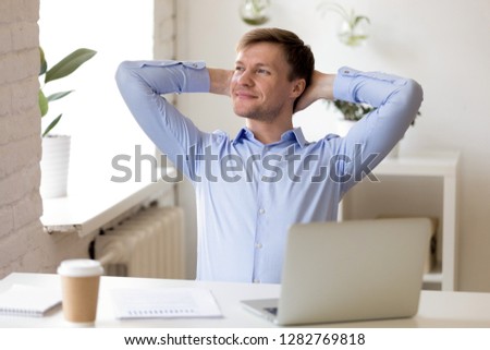 Satisfied businessman relaxing leaning back with hands behind head, enjoying break at workplace, happy man thinking about successful business project, strategy, finish work with laptop, dreaming Royalty-Free Stock Photo #1282769818