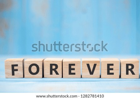 FOREVER wooden cubes on blue table background with copy space for text. Wedding, Romantic and Happy Valentine’s day holiday concept