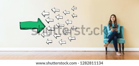 Arrow facing in a opposite direction with young woman holding a tablet computer