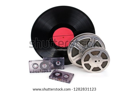 Old film reel with strip black and white cinefilm, photographic film, audio recordings and vinyl records isolated on white background.