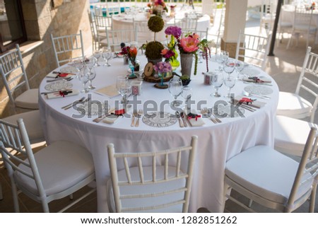 an elegant table with a white tablecloth, flowers and chairs  chiavari Royalty-Free Stock Photo #1282851262