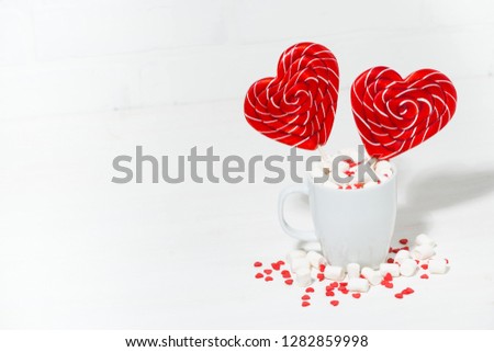 candy on a stick in the form of hearts in a cup on white background, top view horizontal