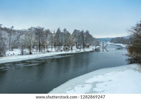 Aerial view from drone of winter landscape with snow and frozen lake or river in ice