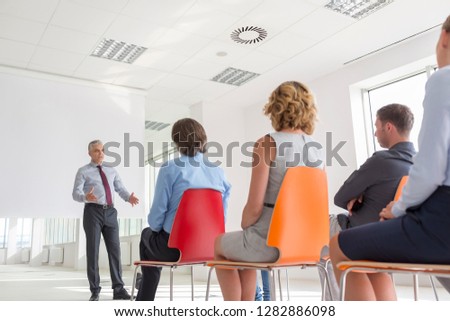 Mature businessman explaining strategy to colleagues at office during meeting
