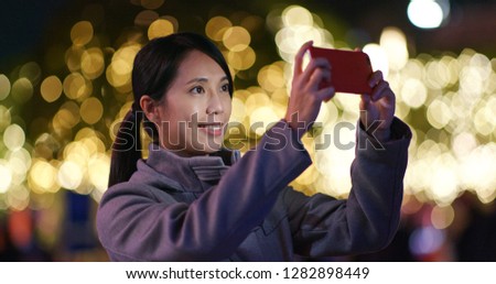 Woman use of cellphone to take photo in the carnival party at night 