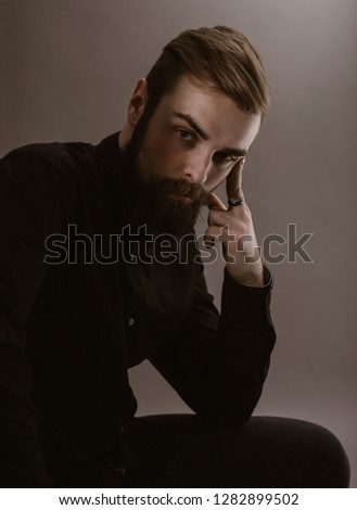 Sepia photo portrait of a pensive man with a beard dressed in the black shirt on the white background