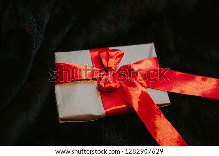 Kraft paper envelope tied with a red ribbon as a gift message. The gift is tied with a red bow against the background of beautiful natural fur.