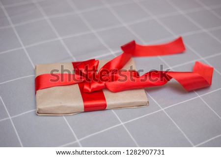 Kraft paper envelope tied with a red ribbon as a gift message. Gift tied with a red bow on a gray background.