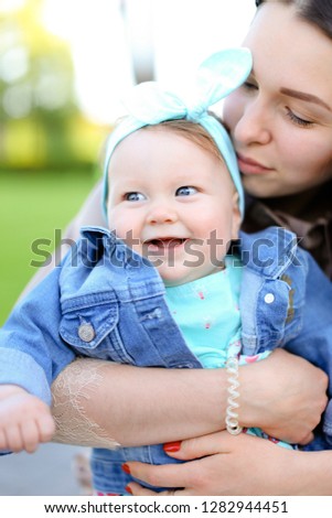 Closeup young european mother kissing little daughter wearing jeans jacket. Concept of motherhood and children.