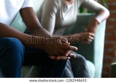 Black married couple spouses quarrelled sitting separately on couch, close up focus on husband body part folding hands together. Break up and divorce, misunderstanding and split in relations concept Royalty-Free Stock Photo #1282948693