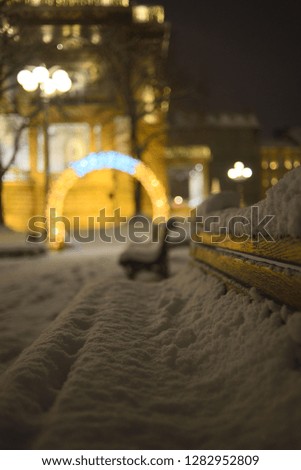 Detail of the benches covered with snow, in the city park, during the winter snowy evening, suitable for large format prints