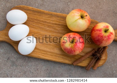 ingredients eggs apples and cinnamon on wooden board view from top
