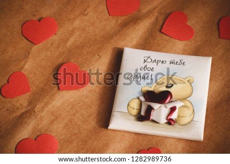 Graft paper background with card a cute bear on it. Bear with Russian words "Giving my heart to you" on it. Red hearts. Valentine's Day- concept.