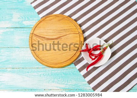 top view of wooden board and striped tablecloth and chili peper