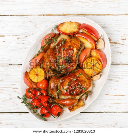 Baked whole little chickens with apples, lemon, garlic, thyme, tomatoes and spices. Selective focus, top view, square picture