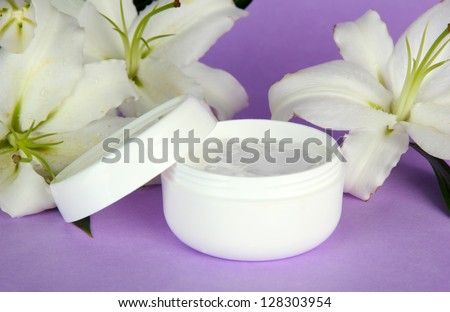 Cosmetic cream and beautiful lily, on purple background