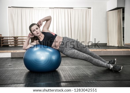 Woman in gym making exercises with big ball