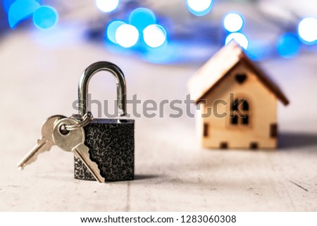 Model of a wooden house with a lock and keys and bokeh on a gray background. Mortgage concept. Selective focus.