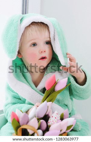 cute baby boy in a rabbit costume with a bouquet of flowers on Mother's Day. Easter Bunny, March 8, Spring