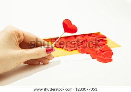 A girl holds a heart in her hand, next to a gold envelope and a lot of hearts, a situation of love in the distance