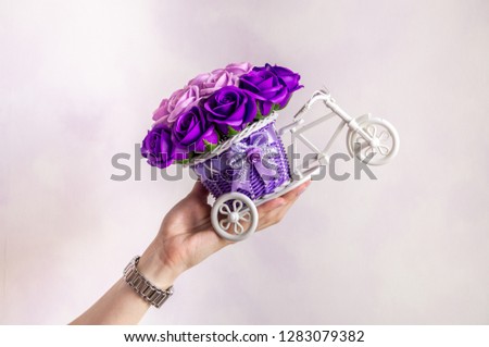 Festive floral decor: a small decorative basket in the form of a forbicycle with purple flower buds.