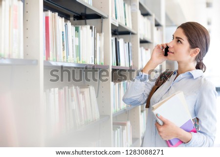 Teenage girl talking on mobile phone in library at university