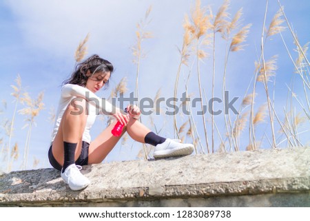A young woman stays hydrated by taking a drink of water from a bottle in between a workout run in the park