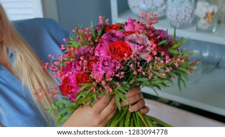 Professional woman floral artist, florist holding and checking beautiful bouquet at workshop, flower shop. Floristry, handmade and small business concept