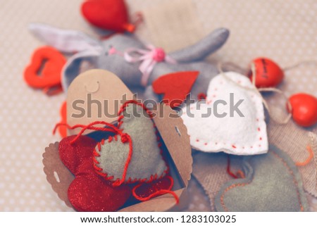 Valentines day. Tilde rabbit lying in a pile of handmade hearts. Valentine Day. Heart pendant. Space for text. Red Hearts. Image toned in trendy color.