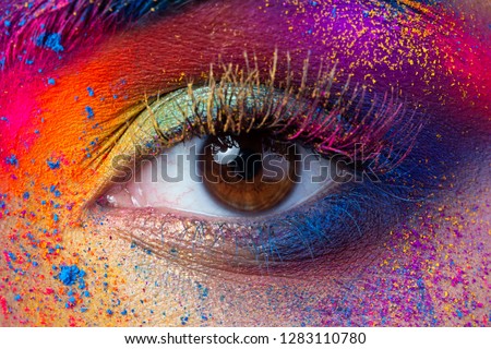 Close up view of female eye with bright multicolored fashion makeup. Holi indian color festival inspired. Studio macro shot Royalty-Free Stock Photo #1283110780